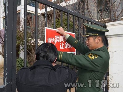 消防官兵和物業人員一起懸掛提示牌